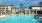 a large swimming pool with palm trees and buildings in the background