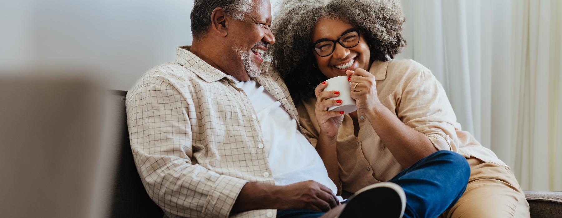 a man and a woman sitting on a couch and drinking from a cup